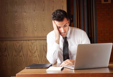 Businessman stressed out while working on his laptop. clipart