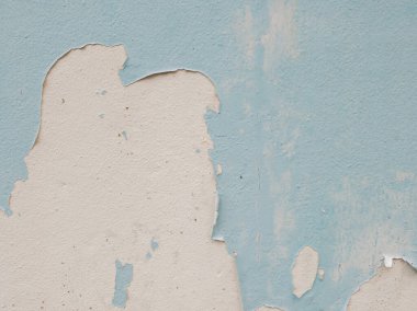 Yakın plan açık mavi boyalı duvar altında gri, pürüzlü beton olduğunu gösteren büyük, kabuk soyma bölümleri var. Eski boya dökülüyor ve çatlıyor.