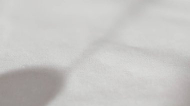 Üzerinde yumuşak gölgeler olan beyaz desenli minimalist yüzeyler. Kumaşın ön planı, ışığı ve gölgesi gibi görünen maddenin ince ve düzensiz dokusuna odaklan..