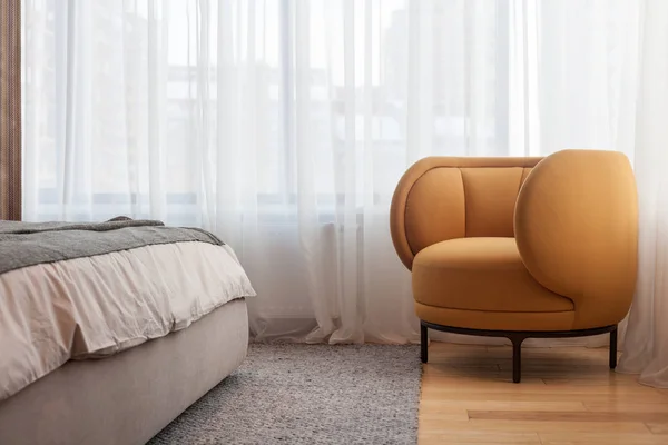 Modern living room with yellow armchair against the background of the window standing next to the bed