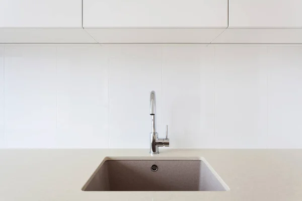Detail of a white rectangular designer kitchen sink with chrome water tap