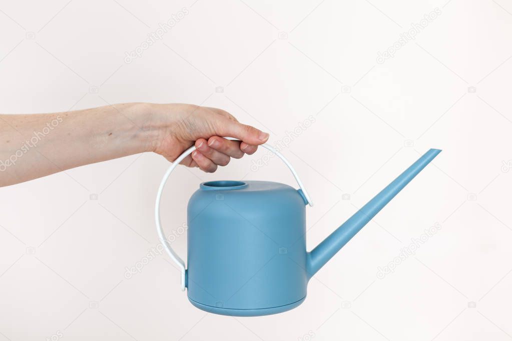 Girl hold a watering-can in her hand on a light background