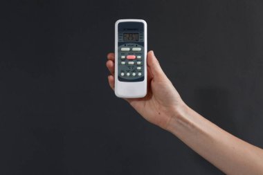 Hand using a remote control to activating air conditioning  on the dark background clipart