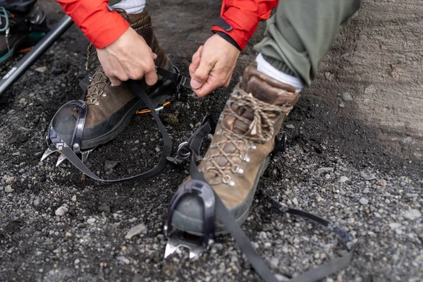 Close up cropped photo of confident strong man pull sling on anti-slip hiking crampons device, focus on shoelace professional boots with vibram sole base