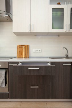 Mutfak koymak için sebze ve malzeme kesim panosu ile bıçak, çatal, kaşık temiz beyaz cook mutfak masasının altında açık ahşap çekmece ile beyaz çini karşı yalın dikey fotoğraf