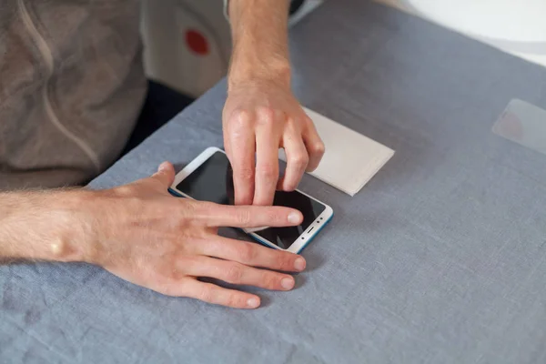 Protect, protective gadget concept. High angle top side profile view cropped photo guy hands wipe digital device screen with an alcohol cloth for glue a new protective glass at home