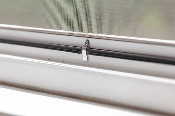 Cropped close up photo of installing mosquito nets for plastic windows. Focus on metal clamping