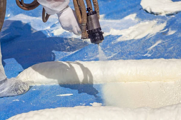 Technician dressed in a protective white uniform spraying foam insulation using Plural Component Spray Gun. Spraying polyurethane foam for roof and energy saving — Stock Image Technician Dressed Protective White Uniform Spraying Foam Insulation Using Plural Stock Photo