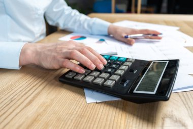 Kırpılan Satış Yöneticisi aracı veya analiz pazarlamacı muhasebe yardımcısı Bayan o hesap makinesi odak parlak çatı iç sayısı yatırımlarında masanın arkasında oturmak yandan onun formal giyim kadar kapatın