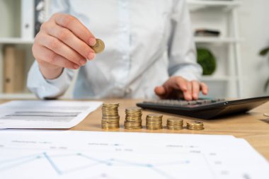 Onun resmi kırpılmış satış yöneticisi veya pazarlamacı Ajan Bayan yakından o kazık sit grafikler grafik grafik hafif çatı iç çalışma alanı'nı kullanmak hesap makinesi ile masanın arkasında para koymak forması giymek