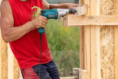 Özel inşaat veya sütun kalıp tahta kartını takma kesici kırpılmış fotoğrafı kapatın. Yetişkin tanınmaz profesyonel işçi matkap onun elinde tutan