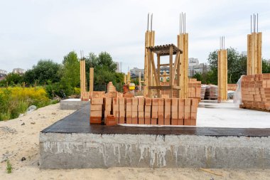 Birden çok satır yeni kırmızı tuğla duvar yapım aşamasında bir evin temeli üzerinde yatıyor. İnşaat Konut konaklama konsepti başlangıcı