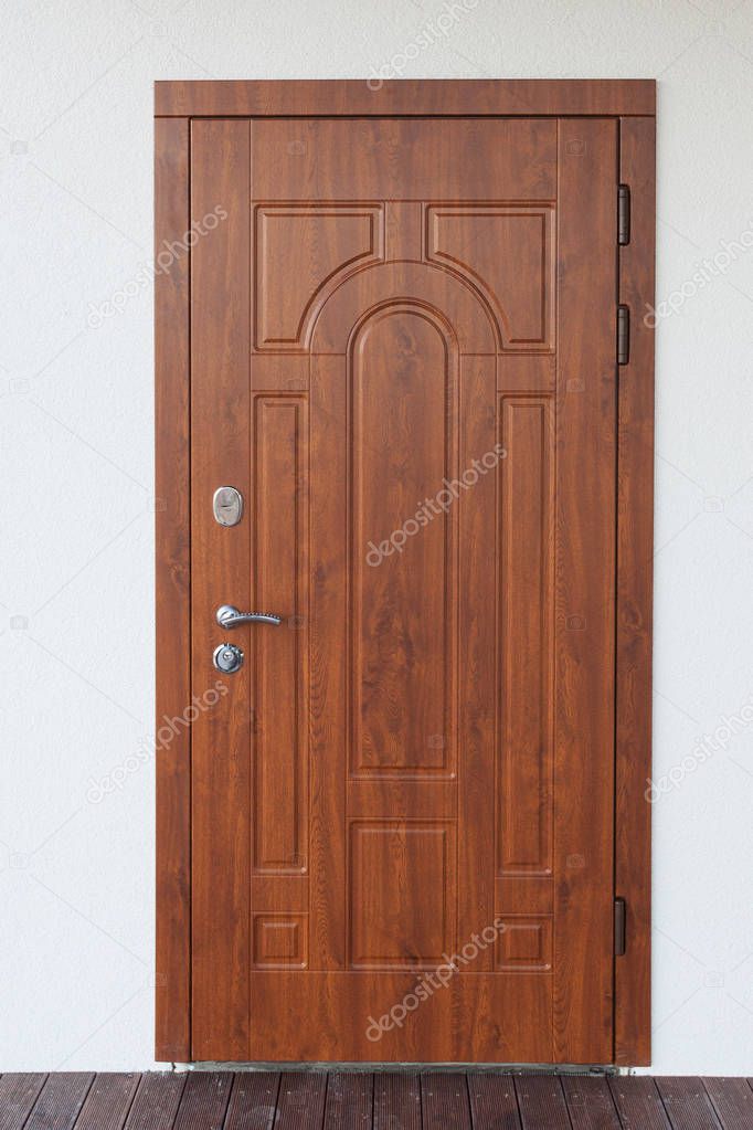 Vertical photo of beautiful metal entrance door on white plaster wall new comfort house