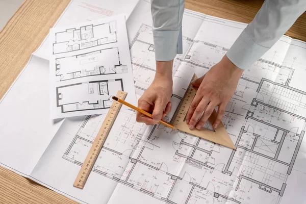 High angle above top view cropped concentrated focused clever intelligent lady in her formalwear shirt she stand at the table in light loft interior hold ruler in hand work with space on blank