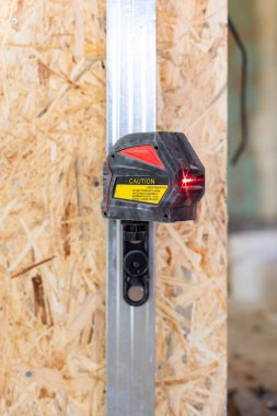 Fotoğraf kırmızı ışın ile switched-on lazer seviye aracının yakın dikey ayağa karşı odaklı strand board paneli ile Oda