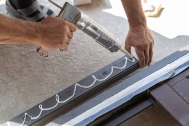 Yetişkin işçi yalıtım ve daha iyi su geçirmez pencere çerçevesi yapmak için dolgu macunu tüp içinde silikon yapıştırıcı kullanarak fotoğraf kapatmak