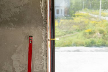Plastik pencere kavramı yükleme. Yeni evin çimento duvara kırmızı düzey aracının fotoğraf
