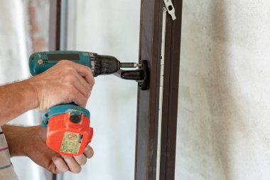 Pencere yükleme kavramı. Yakın fotoğraf tork tornavida ve vida kolu üzerinde yeni plastik pencere kullanarak yetişkin olgun işçi kadar kırpılmış