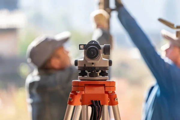 Formwork construction concept. Optical level against blurred background with cooperation between two adult workman working on incomplete object