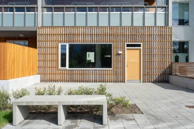 New construction home exterior with contemporary and large windows, bench, stone sidewalk and wooden facade
