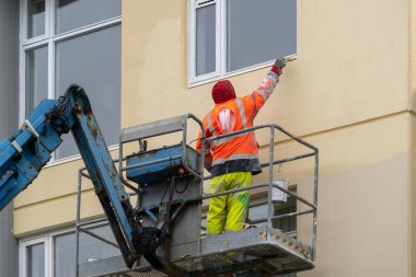 Mekanik iskele üzerinde duran paintbrush boyama çok katlı bina ile olgun işçi adamın arka arkaya fotoğraf