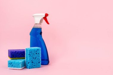 İçin pencere eşiği ve cam ayakta pastel pembe arka plan metin için boş alan ile izole mavi sünger yakınındaki deterjan sprey şişe fotoğrafı