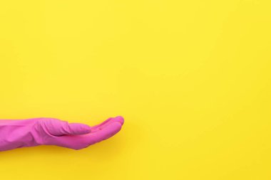 Metin için boş yer sarı zemin üzerine pembe lastik eldiven el palm görünmez ürün gösterilen kadar tutan kadında izole