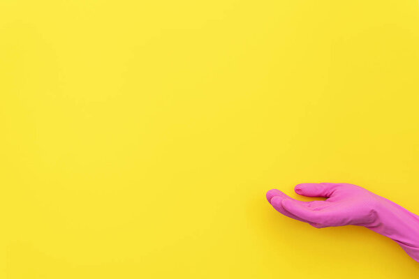Woman in pink gloves holding hand palm up showing invisible product isolated on yellow background with empty space for text