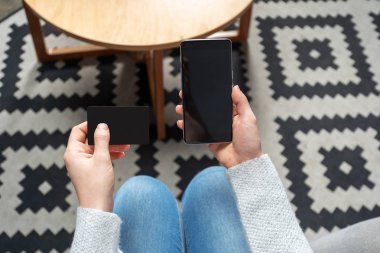 Kartı ve ellerinde taşınabilir telefon donanımları ile yukarı, yukarıdan ve Bayan kırpılmış fotoğrafı yukarıda yüksek açı yakın. Loft Restaurant'ta iç mekan içinde oturan