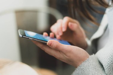 Yan görünümü profil ve taşınabilir telefon donanımları ile Bayan kırpılmış fotoğrafı kadar elinde kapatın. Loft Restaurant'ta iç mekan içinde oturan