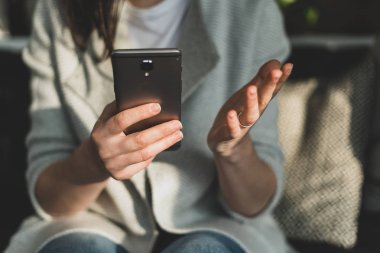 Loft Restaurant'ta iç mekan içinde oturan Bayan kırpılmış fotoğrafı kapatın. Taşınabilir telefon donanımları elinde tutan ve avuç gösterilmesini