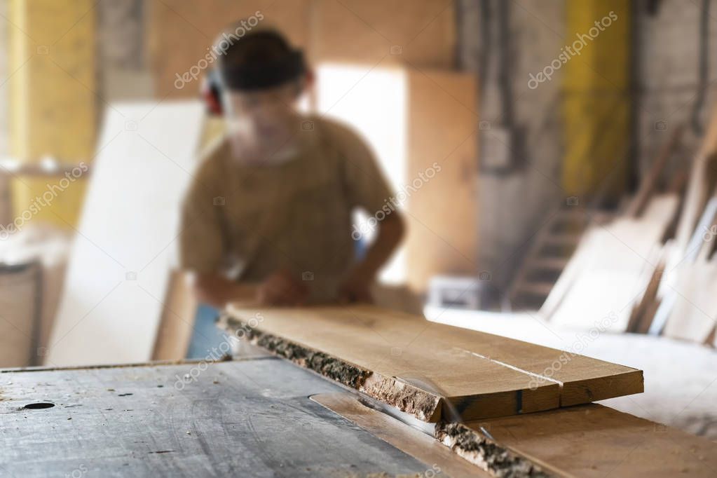 Manual wood small business concept. Cabinetmaker or unrecognizable mature handyman push wooden plank board on saw table make furniture in garage or workroom