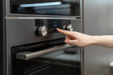 Yan görünümü fotoğraf kadın el seçin veya elektronik kontrol panelindeki siyah mutfak dolap yerleşik fırında için program geçiş