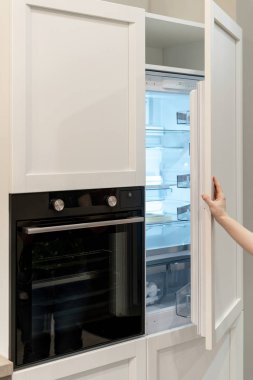 Beyaz modern boş dondurucu yerleşik mutfak dolap modern fırın ile açma kadın el dikey fotoğraf