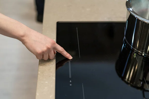 Side view photo of woman hand turning or switch on induction ceramic stove