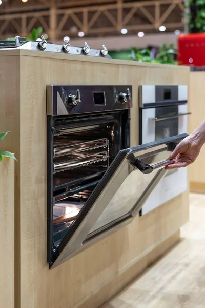 Foto Vertikal Wanita Membuka Pintu Oven Modern Baru Dengan Cahaya — Stok Foto