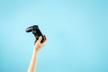 Pastel mavi arka planda izole ellerde siyah joystick