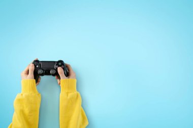 Açık mavi arka planda izole kız elleri siyah joystick