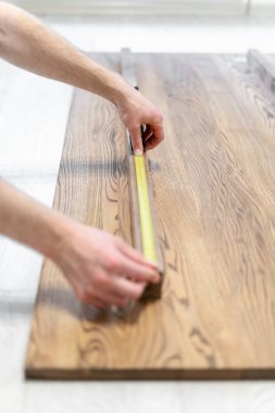 Rulet bandı kullanan ve ahşap masa üst boyutunu kontrol adam