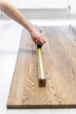 Rulet bandı kullanan ve ahşap masa üst boyutunu kontrol adam