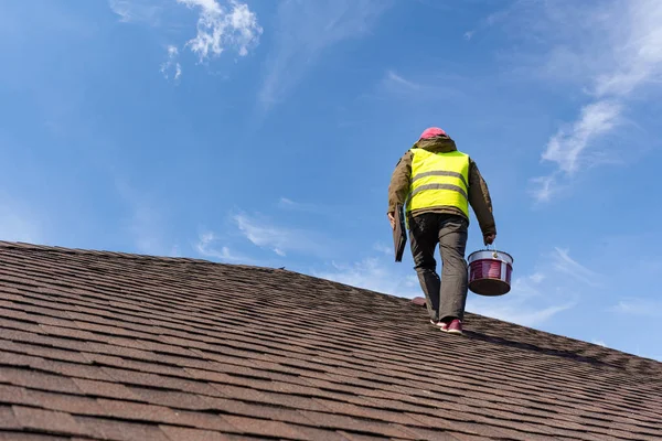 Працівник стоїть на даху плитки нового будинку під будівництвом — стокове фото