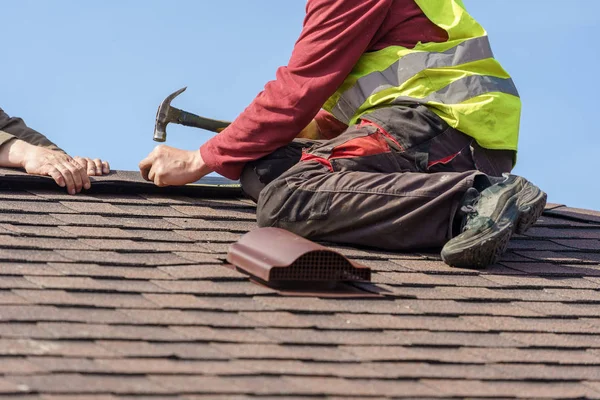 Працівник встановлює елемент черепичного даху на новий будинок під будівництвом — стокове фото