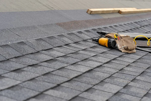 Asphalt atap ubin dan alat sabuk tergeletak di rumah baru di bawah constru — Stok Foto