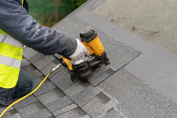 Workman using pneumatic nail gun install tile on roof of new hou — Stock Photo, Image