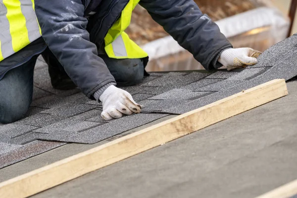 Працівник встановлює плитку на дах нового будинку під час будівництва — стокове фото