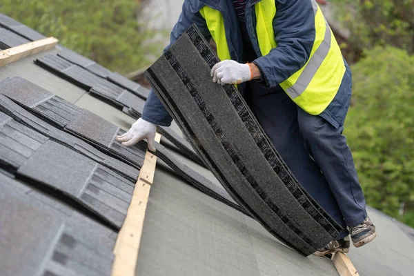 Workman instalar baldosas en el techo de la casa nueva en construcción — Foto de Stock
