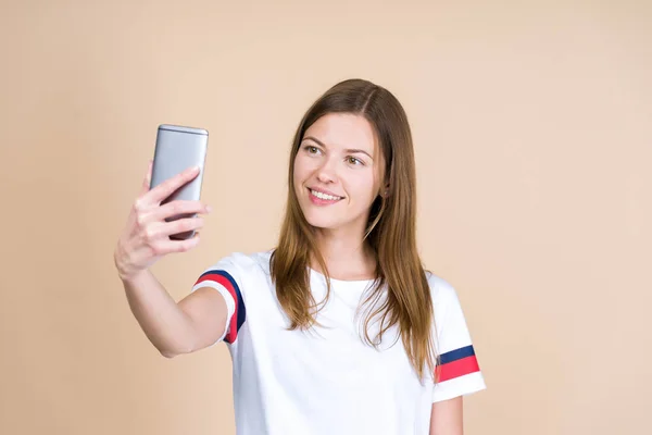 Mujer joven de pie sobre fondo beige pastel, tomando selfie —  Fotos de Stock