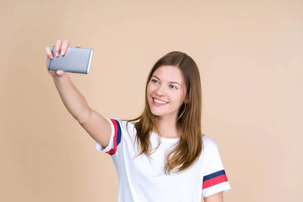 Mujer joven tomando selfie, de pie sobre fondo beige pastel w —  Fotos de Stock