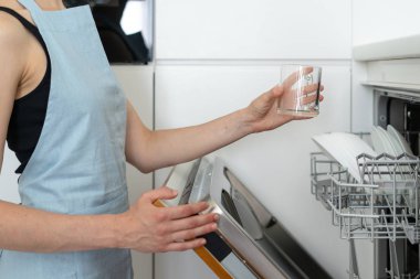 Elinde temiz bardak tutan plakalar ile açılan modern bulaşık makinesi