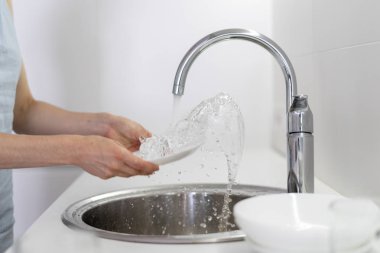 Beyaz mutfakta lavaboda kadın yıkama plakası